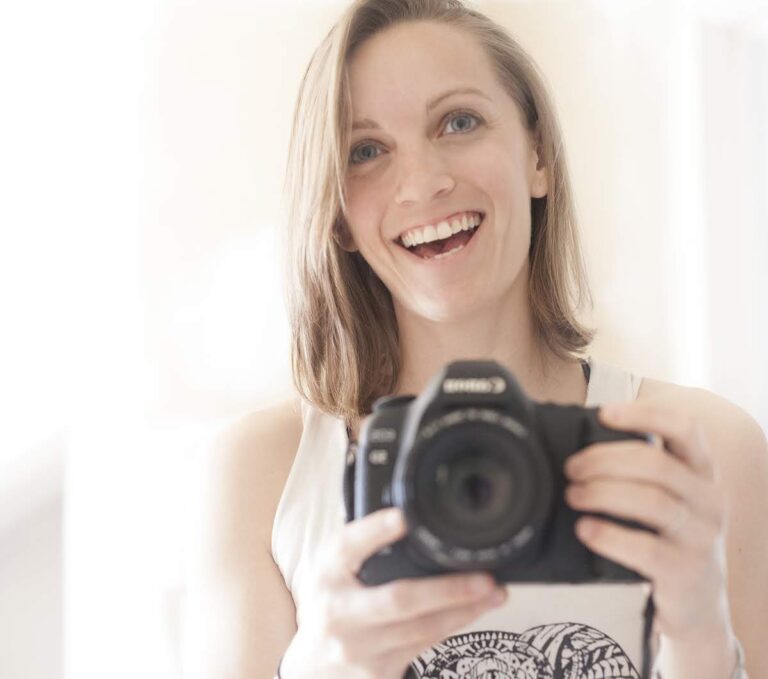 Smiling woman holding a Canon camera.